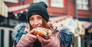 A woman enjoying a PepperJax cheesesteak with the Arc4 logo visible
